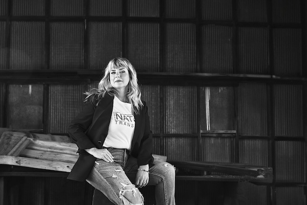 NATCO on Trucking Autonomy Black-and-white photo of NATCO Transport VP and co-owner Cori Eckley-Ritchards in a dark blazer and white T-shirt, and jeans.
